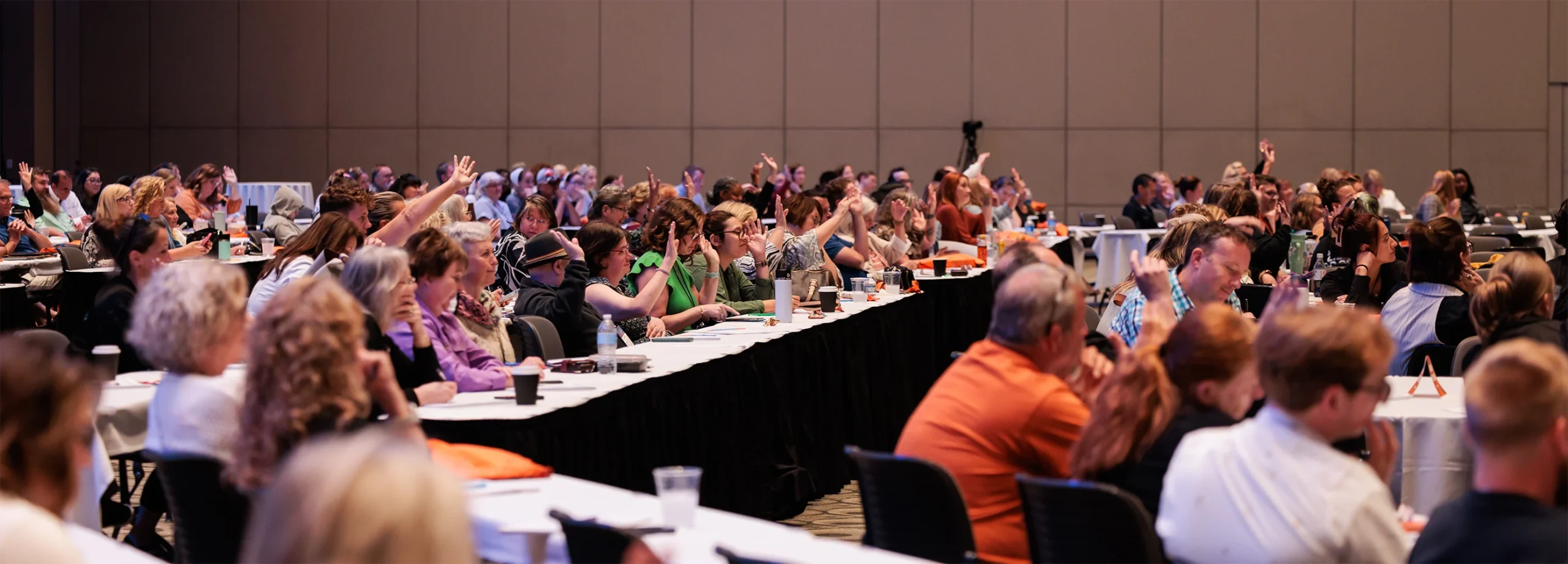 A ballroom of independent retailers at the Retail Success Summit, many with their hands raised